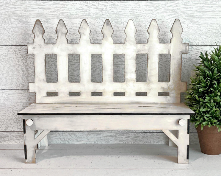 Wooden bench with picket fence design against a wooden wall.