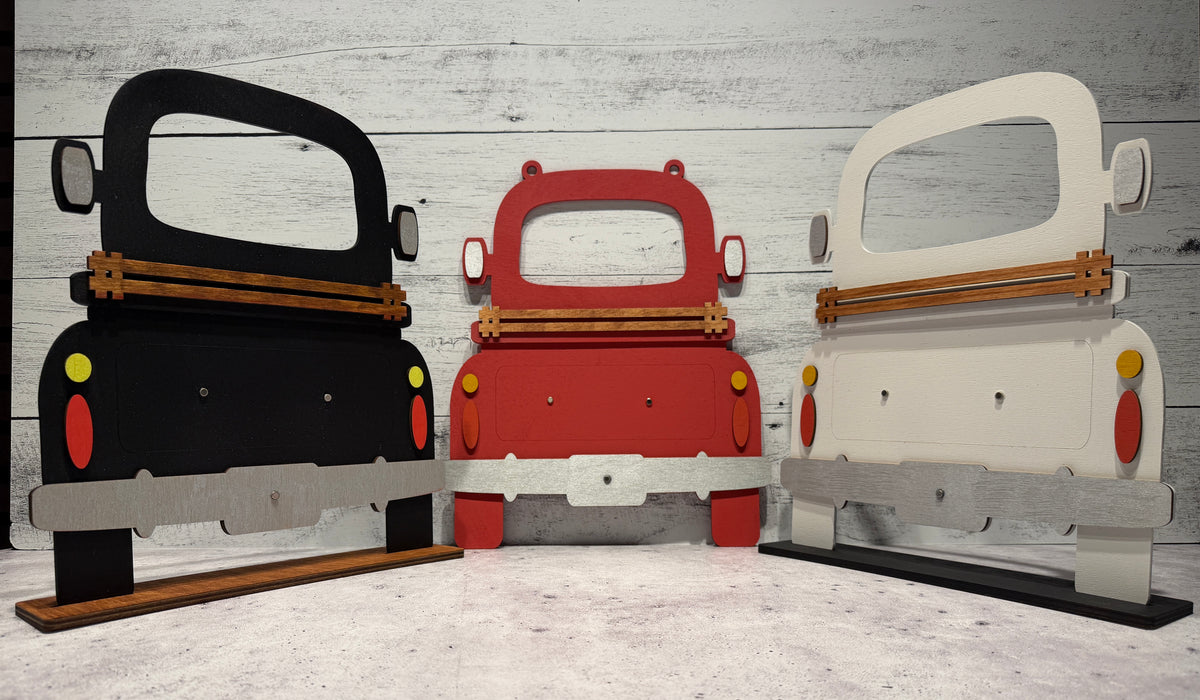 Three cardboard cutouts of cars in black, red, and white on a wooden floor.