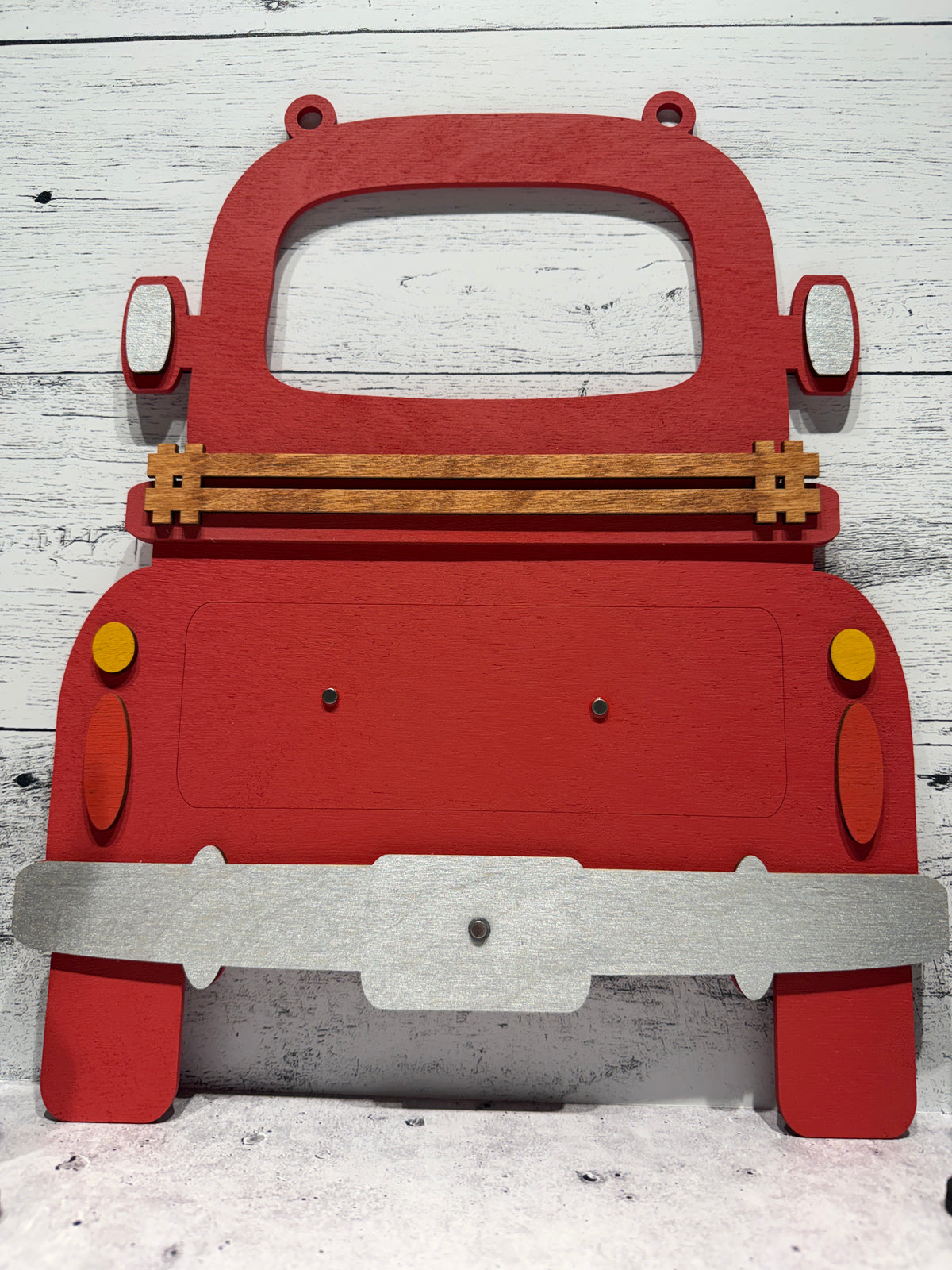 Red toy truck with wooden axles on a white wooden surface
