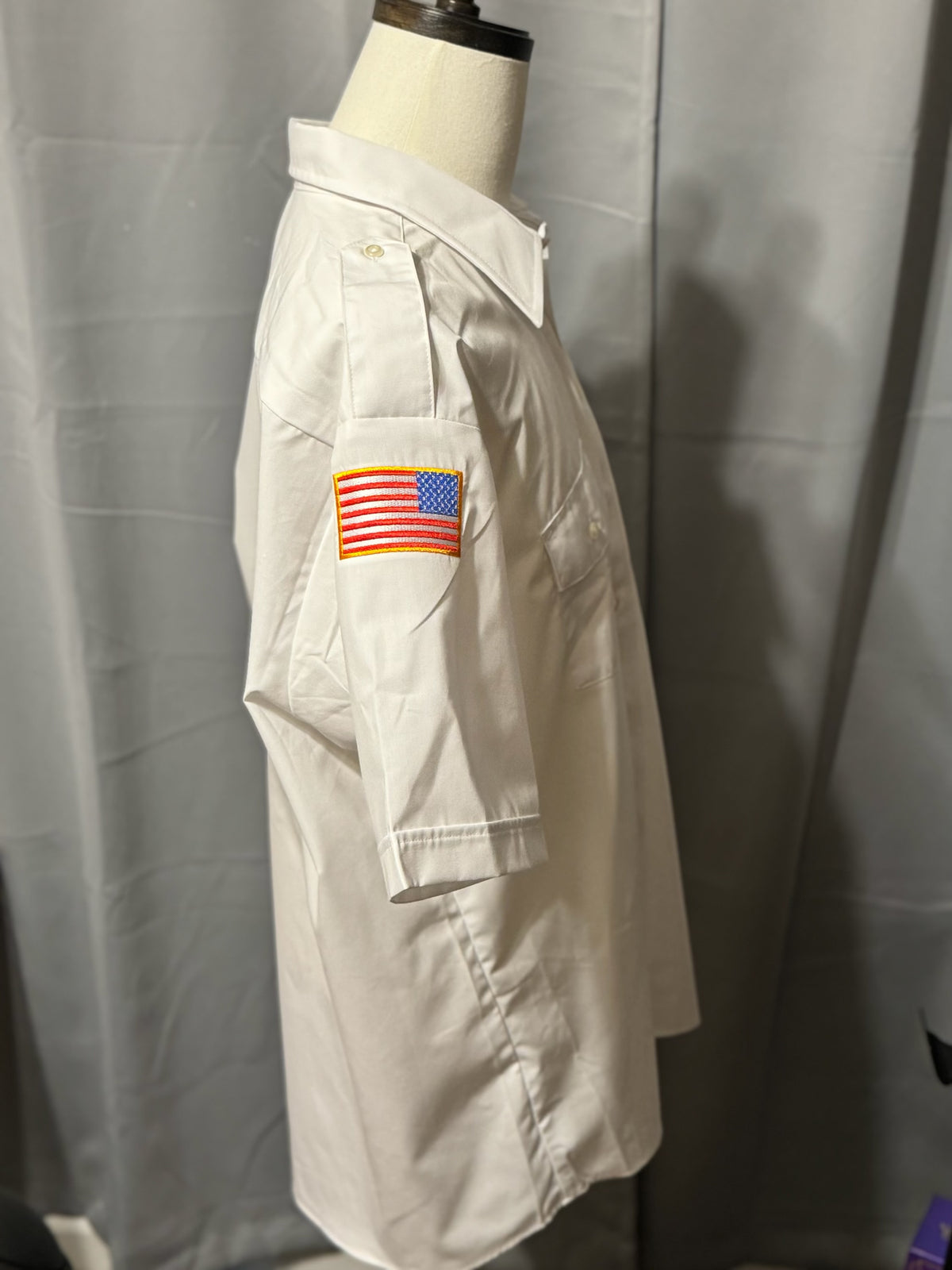 a white shirt with a flag patch on the sleeve