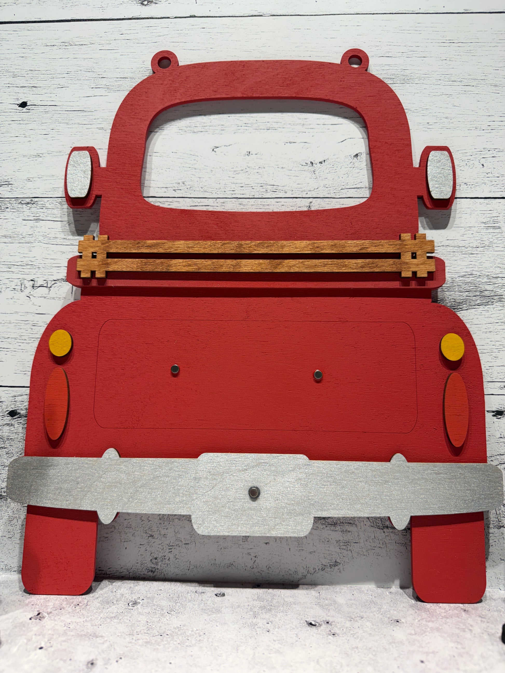 Red toy truck with wooden axles on a white wooden surface