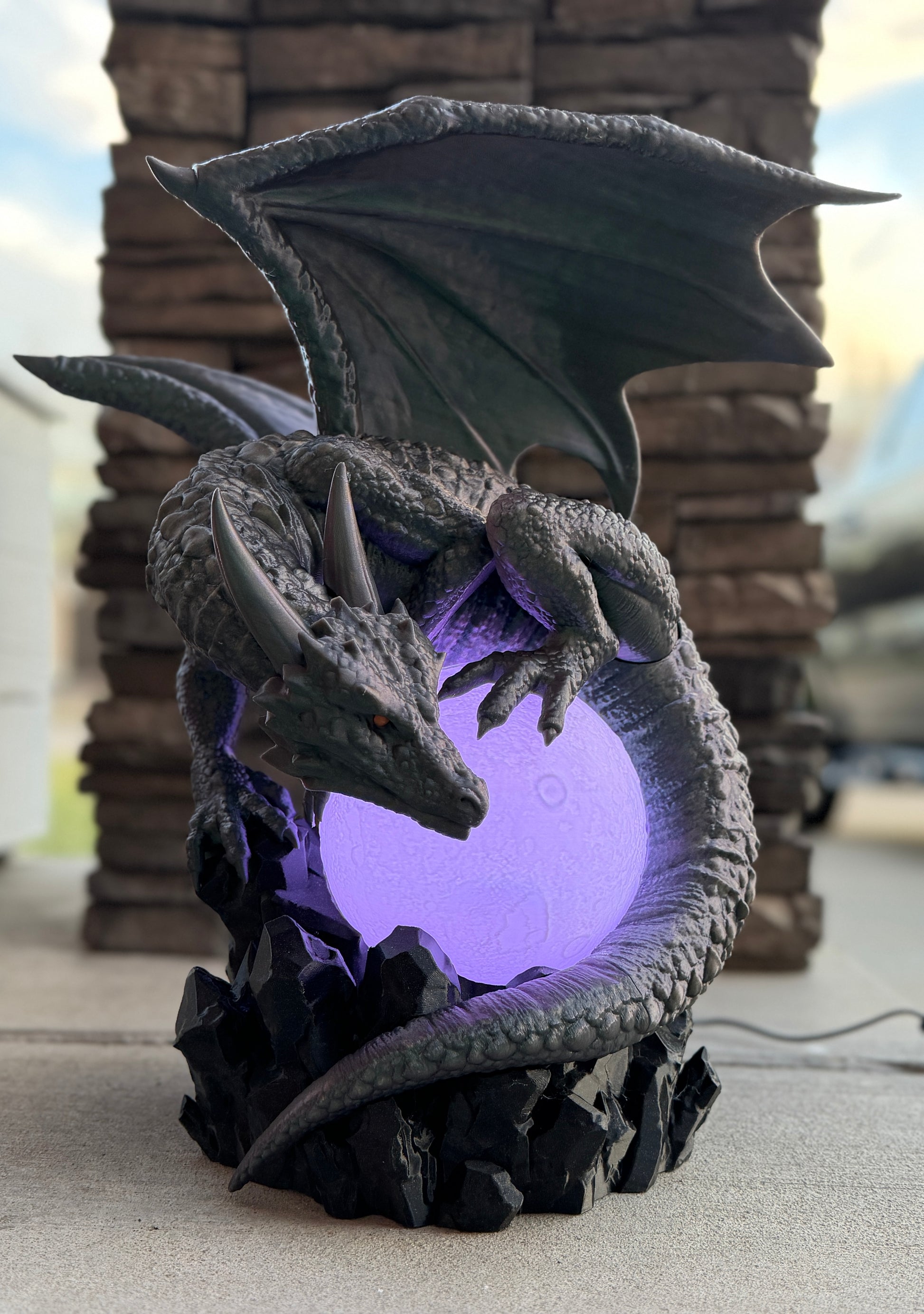 Dragon-shaped lamp with a purple light inside, outdoors.