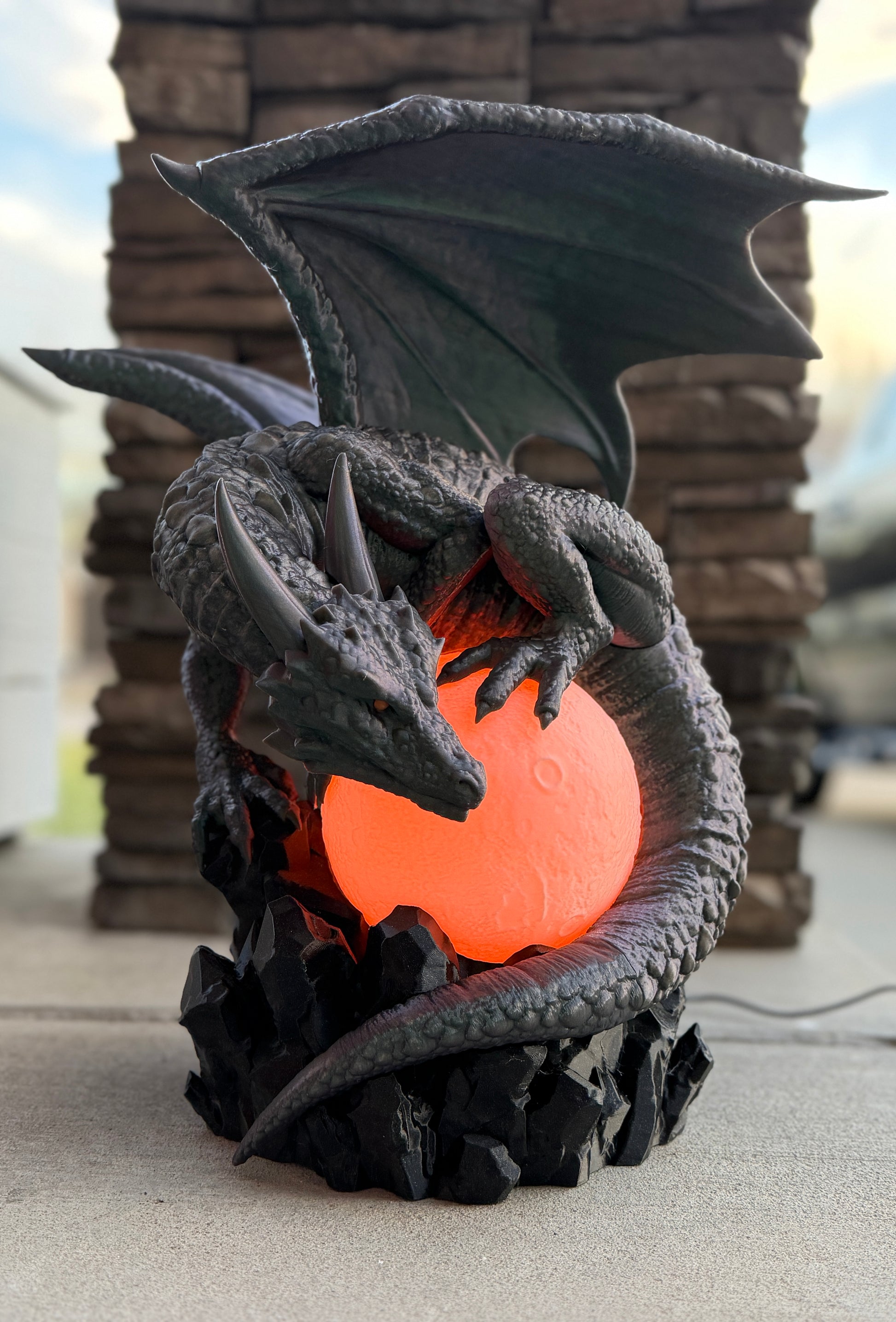 Dragon-shaped lamp with glowing orange core on a stone surface