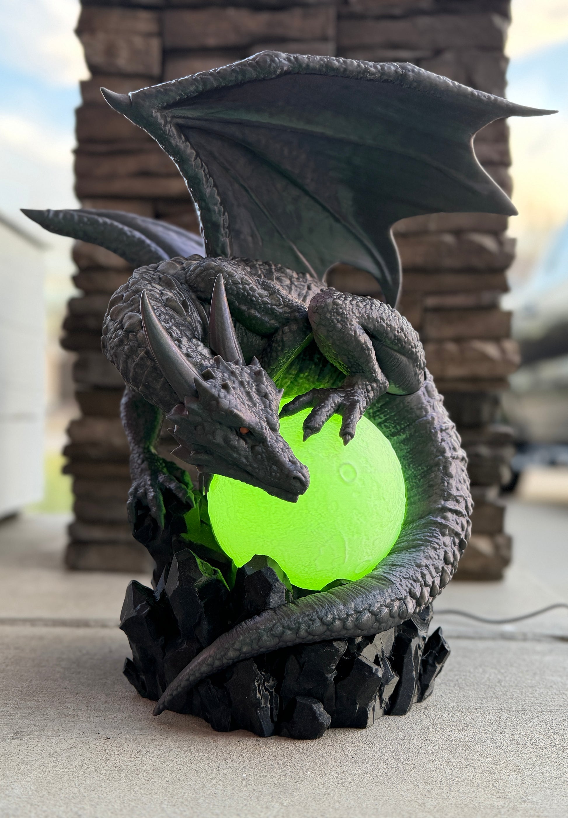 Dragon-shaped lamp with a glowing green core on a stone surface.