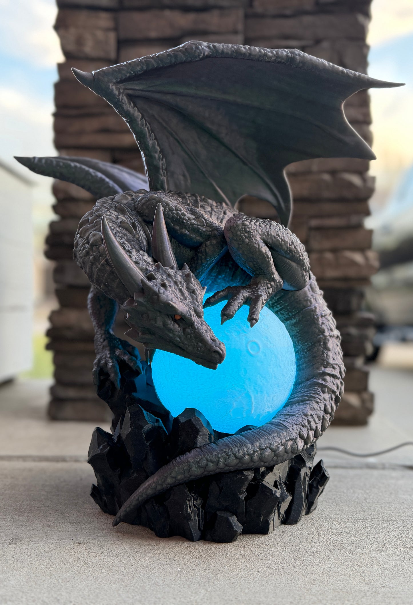 Dragon-shaped lamp with a blue light on a stone surface