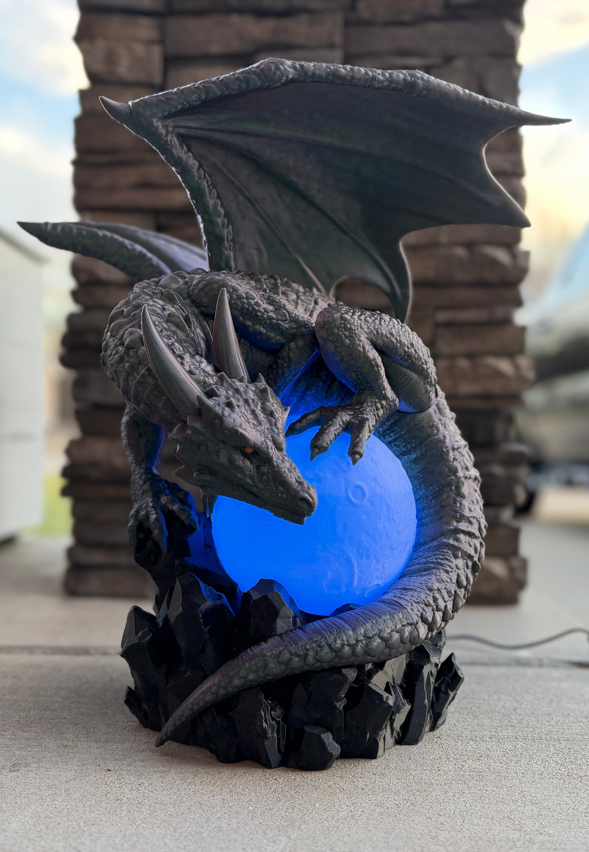 Dragon-shaped lamp with blue light inside, outdoors.