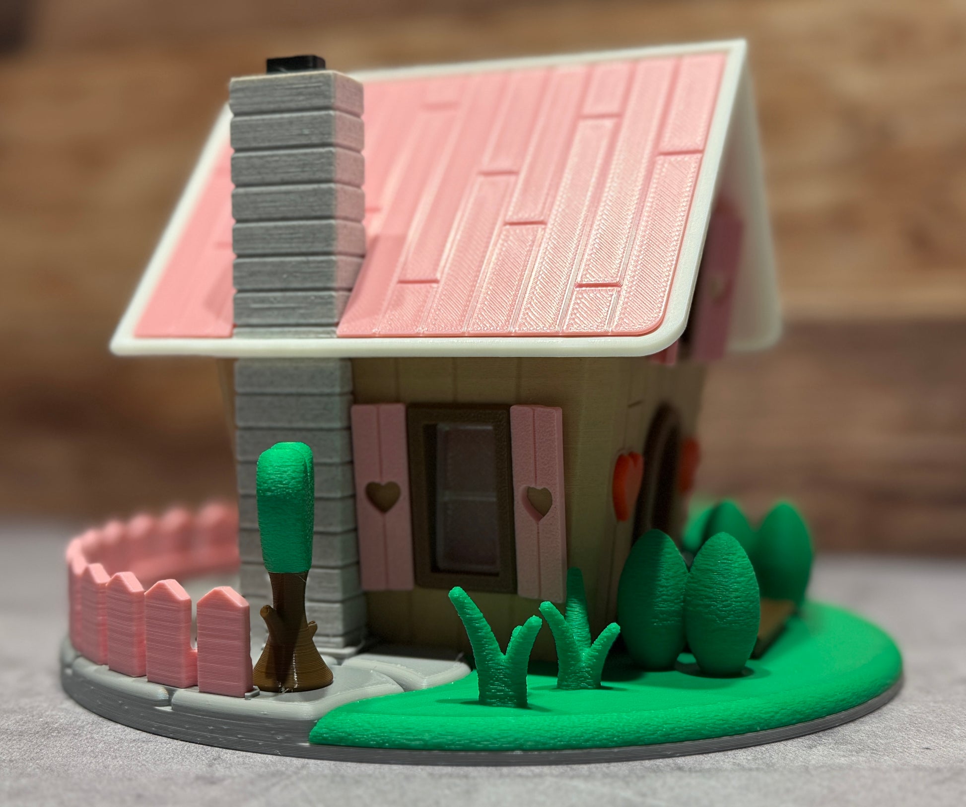 Small model house with pink roof and greenery