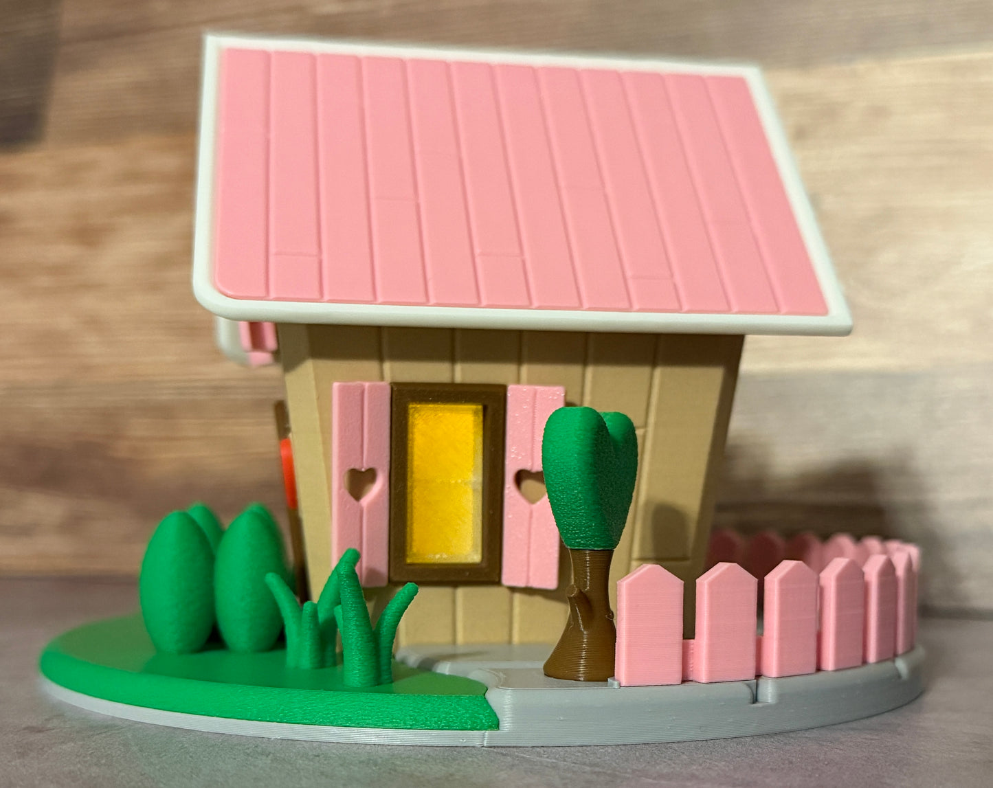 Toy house with pink roof, yellow door, and greenery