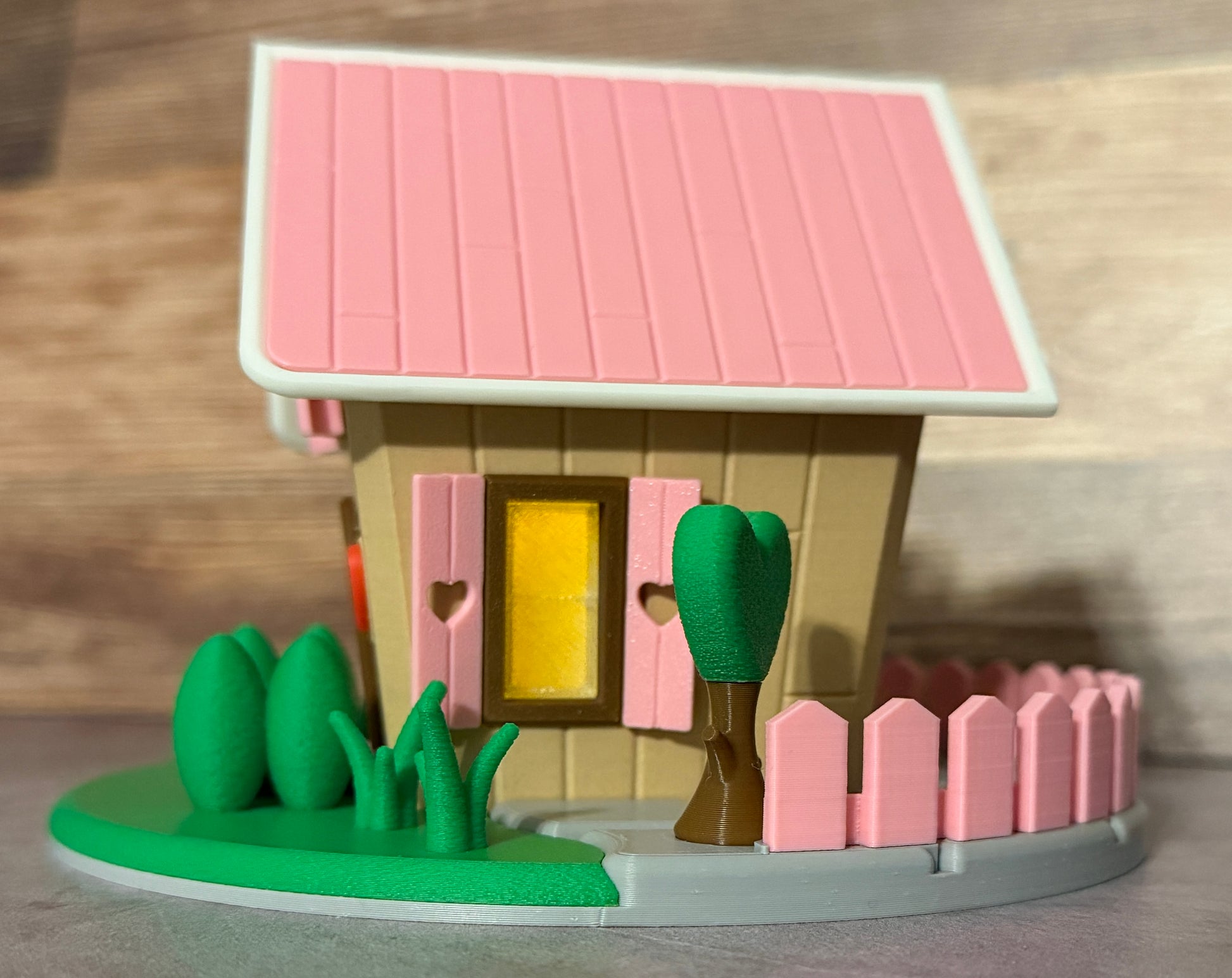Toy house with pink roof, yellow door, and greenery