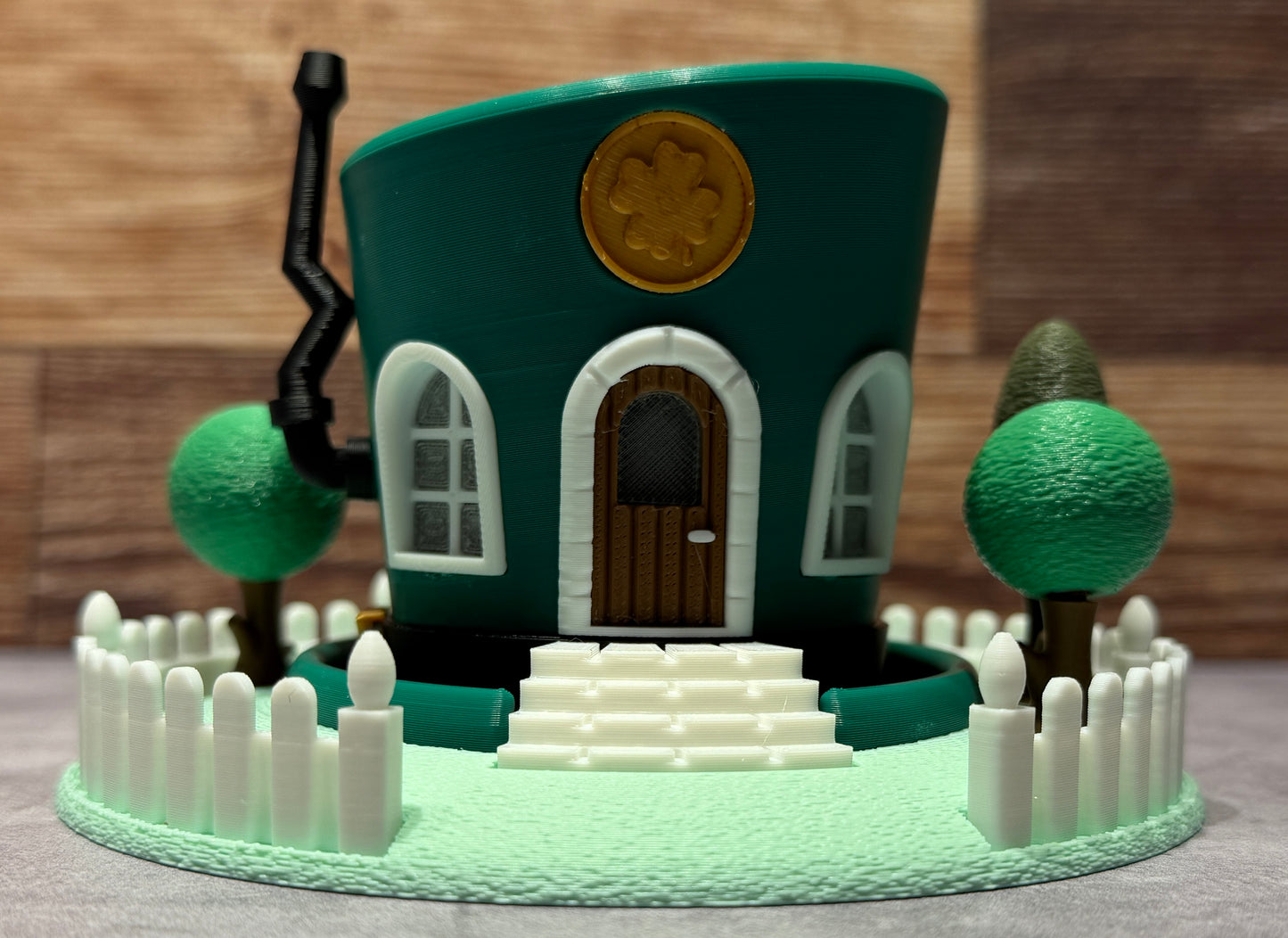 Small model of a house with a green roof and white picket fence