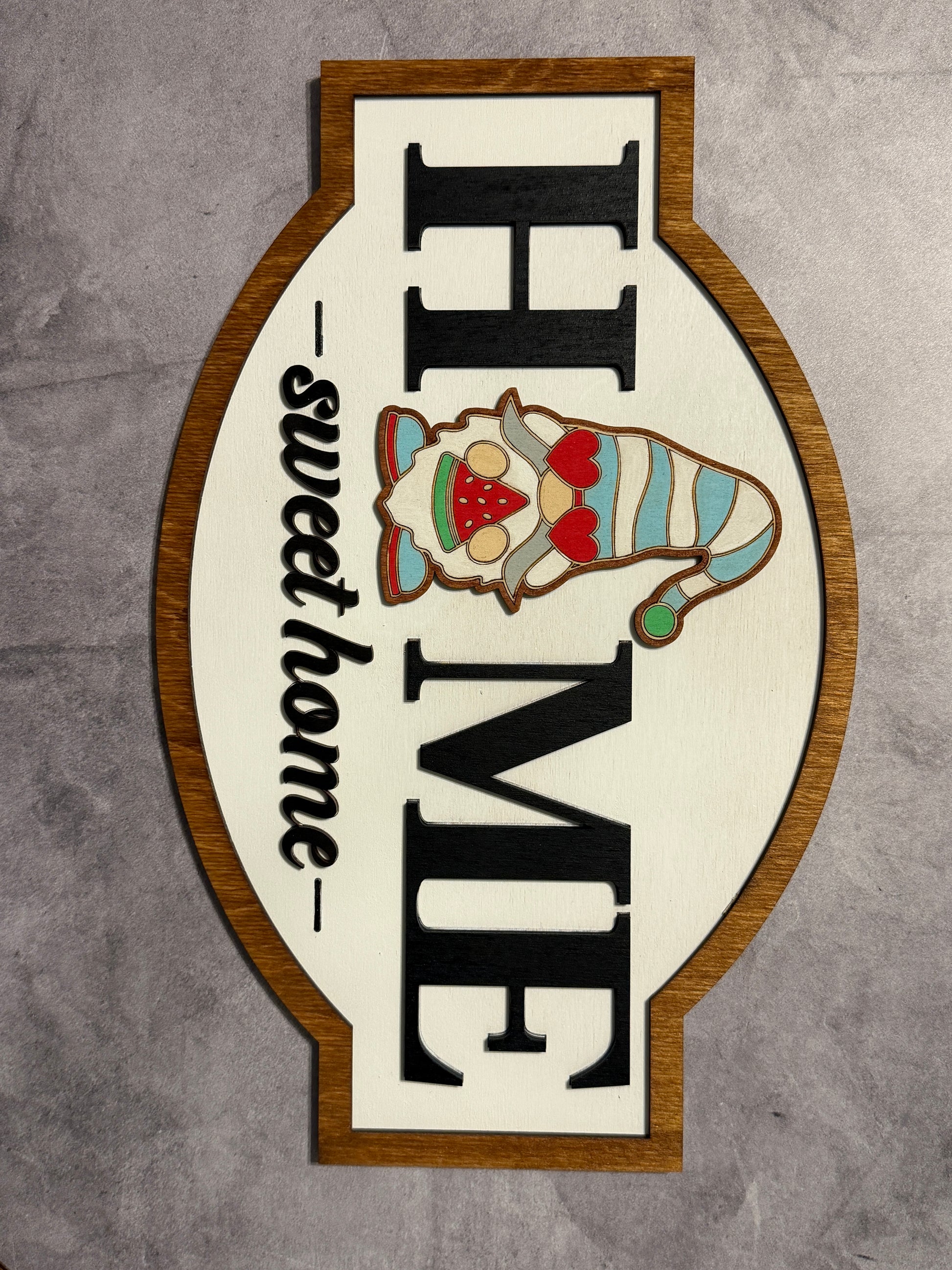 Decorative sign with gnome illustration and 'Home sweet home' text on a gray background