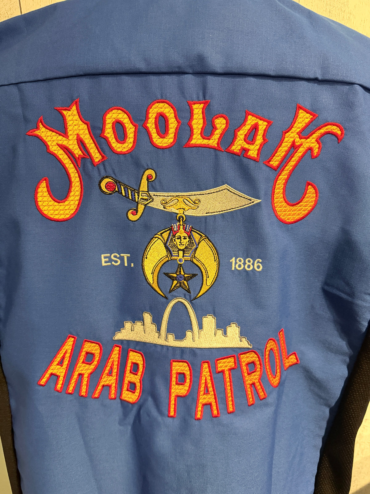 a blue jacket with red text and a sword on it