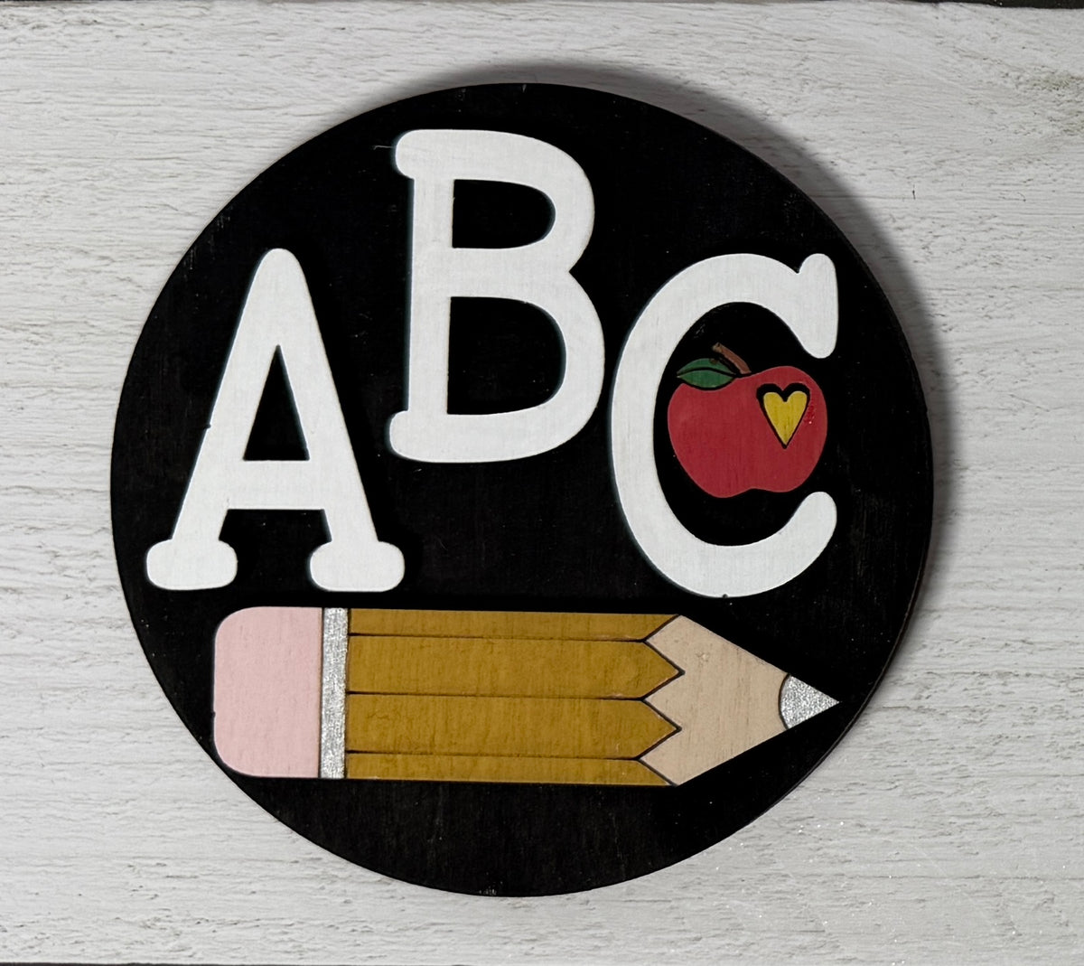 a black circle with white letters and a pencil on it