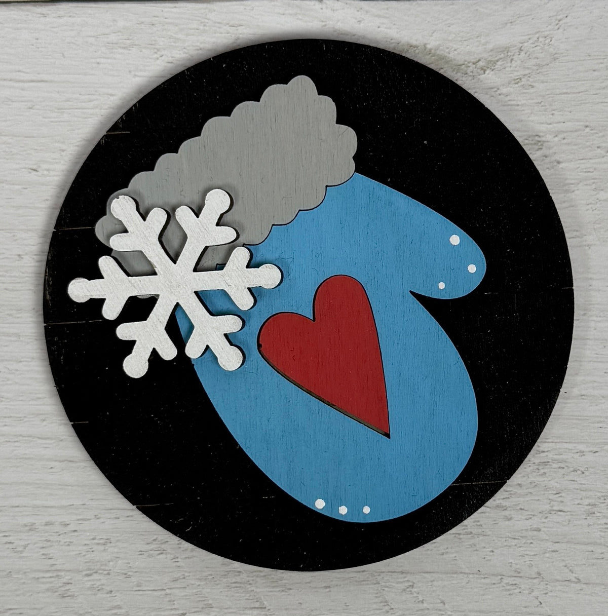 a black circle with a blue mitten and a white snowflake on it