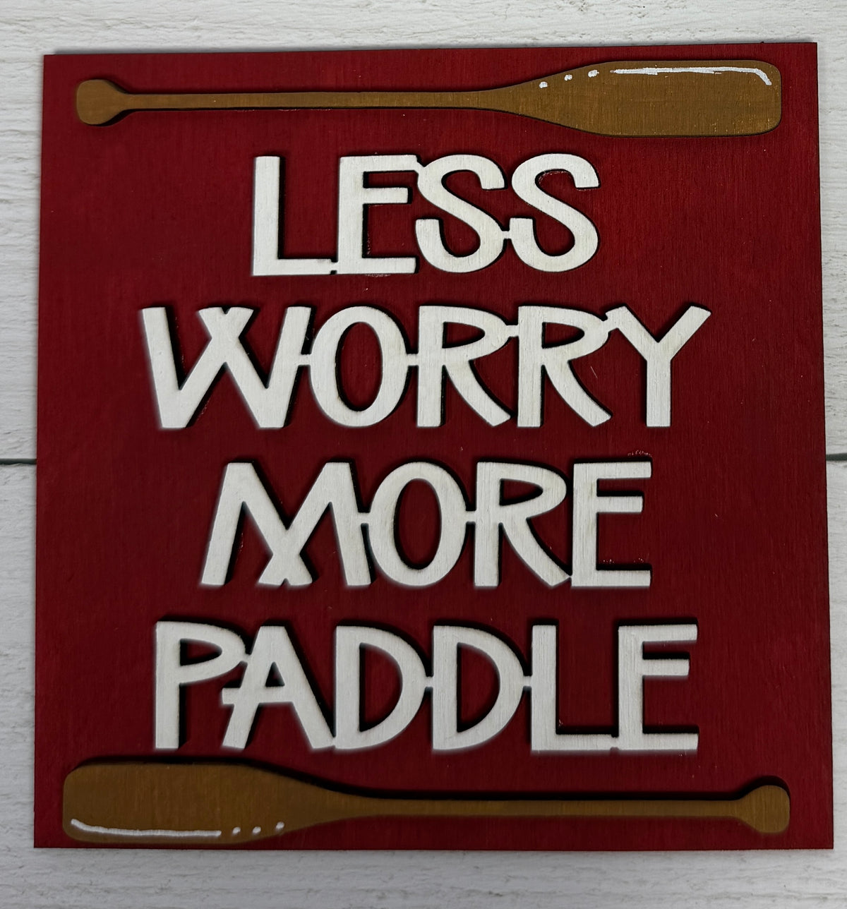 a sign with white letters and brown paddles on a white surface